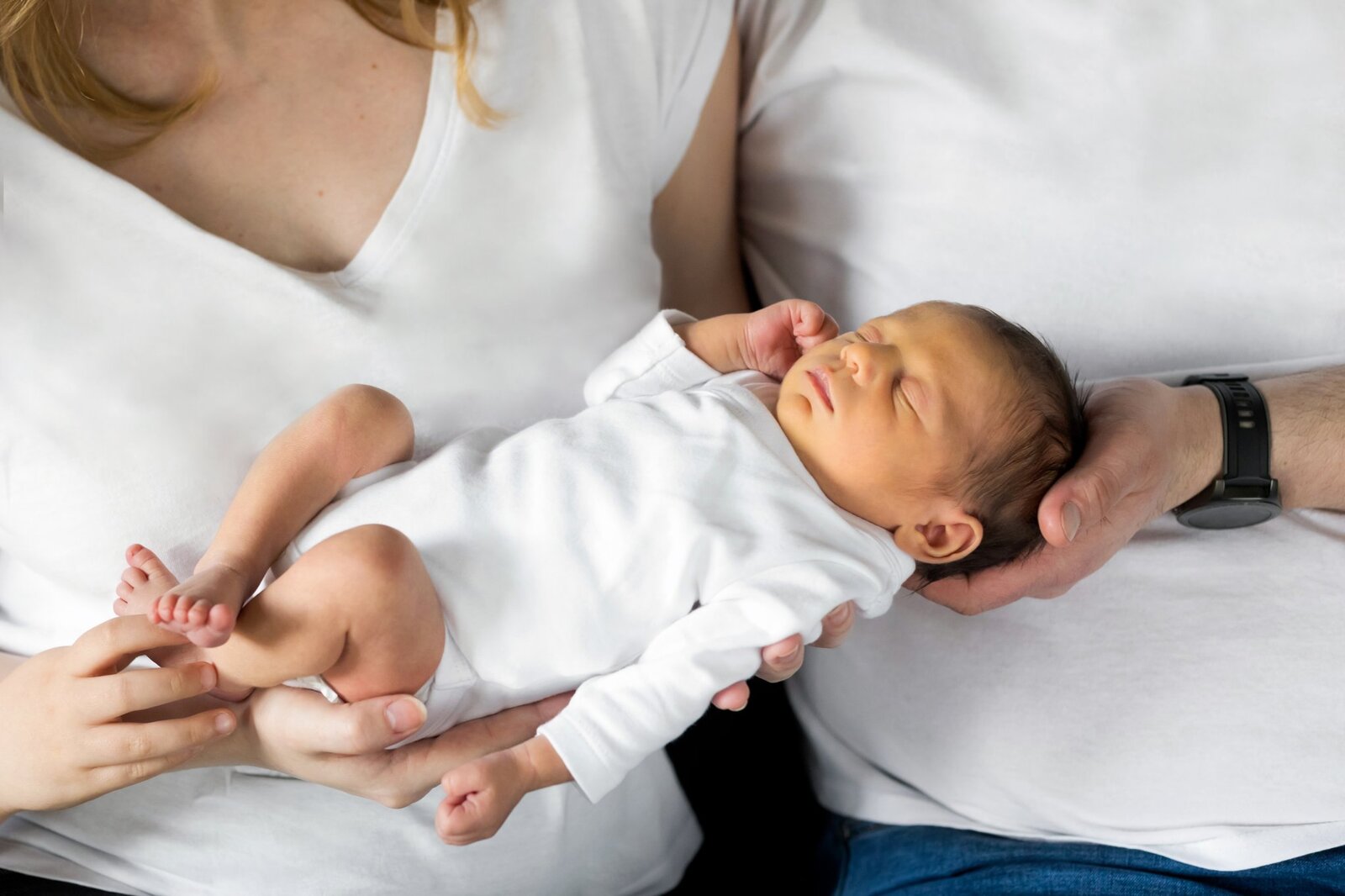 Lifestylowa sesja noworodkowa w domu - rodzina ubrana w jeansy i białe koszulki, a w roli głównej nowonarodzona dziewczynka