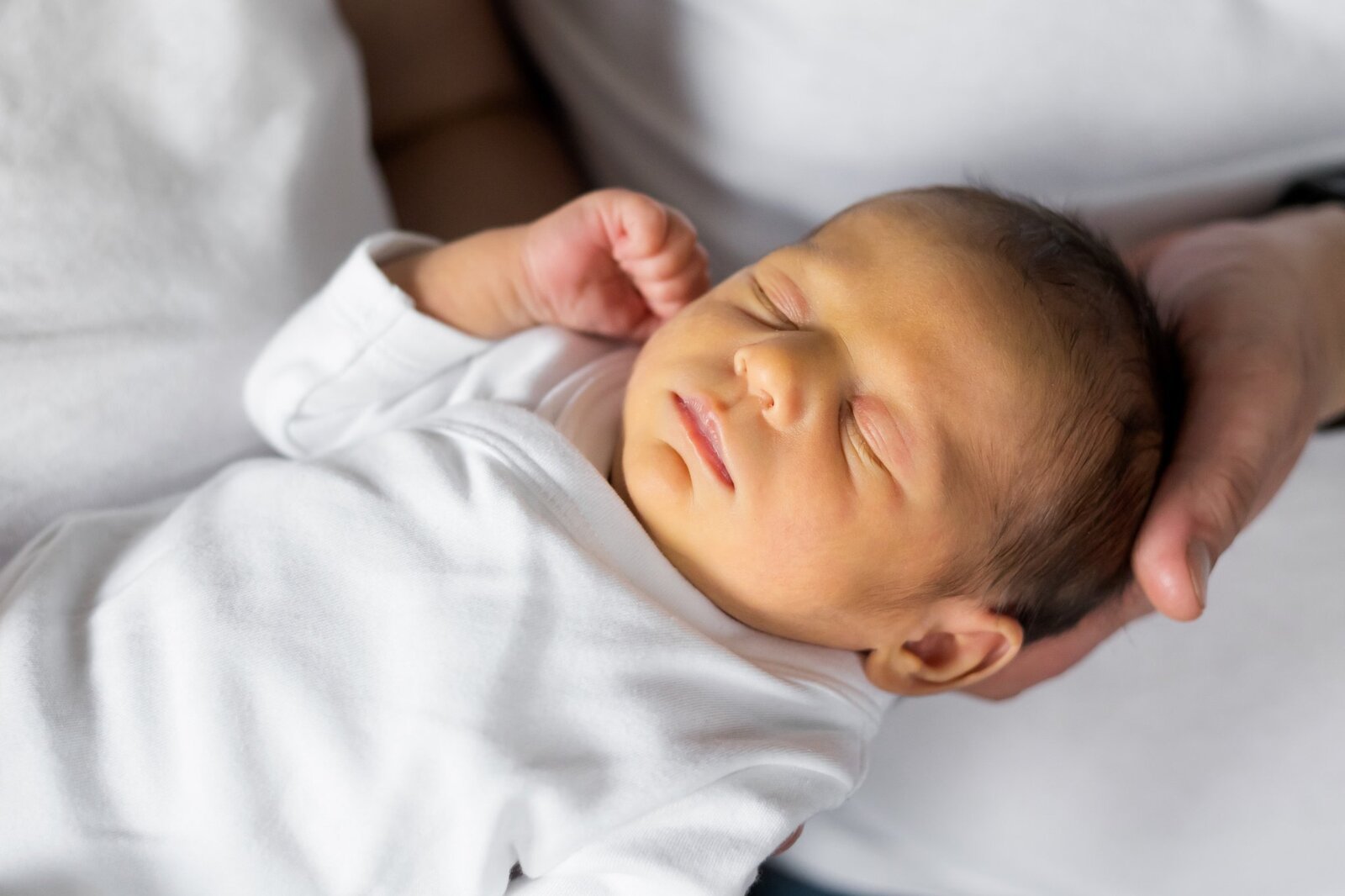 Lifestylowa sesja noworodkowa w domu - rodzina ubrana w jeansy i białe koszulki, a w roli głównej nowonarodzona dziewczynka