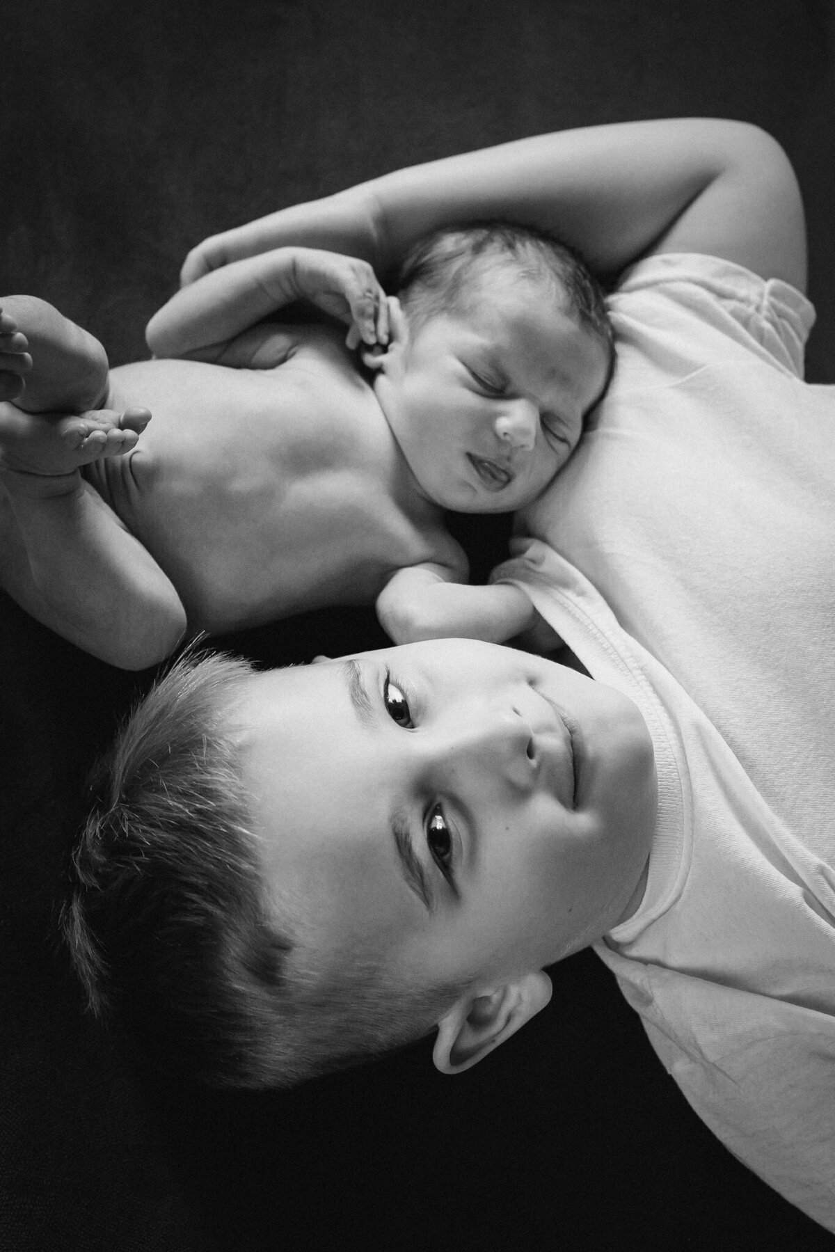 Lifestylowa sesja noworodkowa w domu - rodzina ubrana w jeansy i białe koszulki, a w roli głównej nowonarodzona dziewczynka