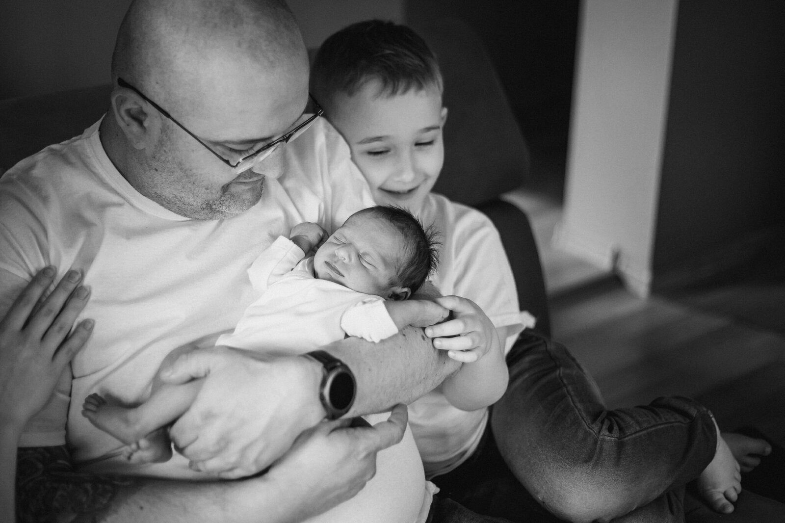 Lifestylowa sesja noworodkowa w domu - rodzina ubrana w jeansy i białe koszulki, a w roli głównej nowonarodzona dziewczynka