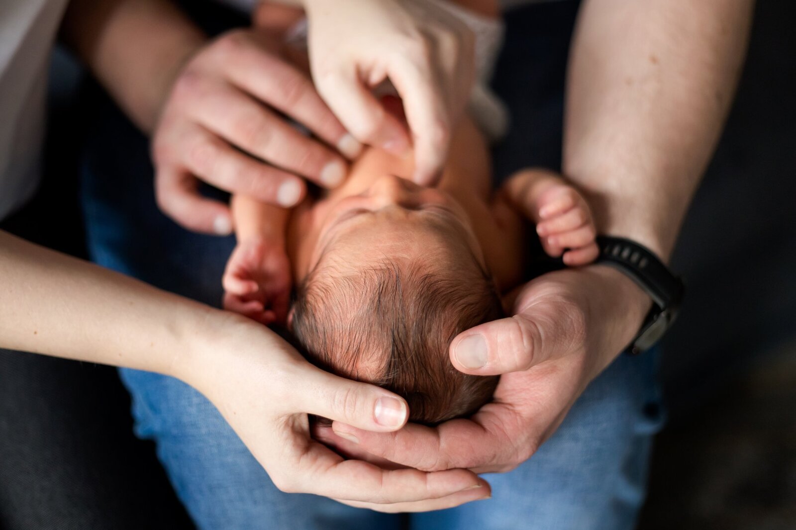 Lifestylowa sesja noworodkowa w domu - rodzina ubrana w jeansy i białe koszulki, a w roli głównej nowonarodzona dziewczynka